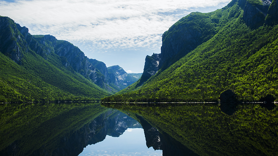 Le majestueux fjord d'eau douce de Western Brook Pond dans le parc national du Gros-Morne, avec ses falaises verdoyantes se reflétant dans l'eau.
